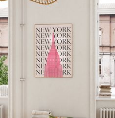 a living room with white walls and a pink art piece hanging on the wall next to a window