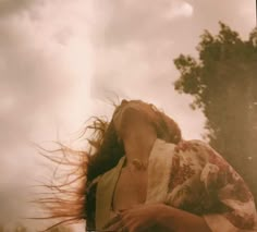 a woman with her hair blowing in the wind, looking up at something behind her