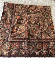 a brown and orange paisley print blanket on a bed