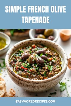 a bowl filled with olive tapenad next to bread and olives on the side