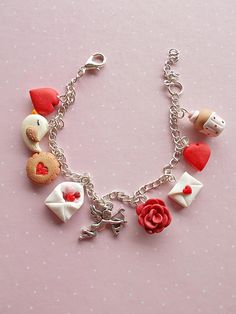 a close up of a bracelet on a pink surface with hearts, flowers and other items