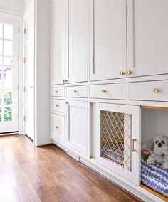 a dog bed in the middle of a room with white cabinets and wood flooring