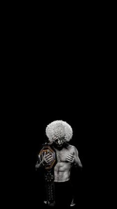 a man with an afro holding a wrestling ring in his hands and standing against a black background