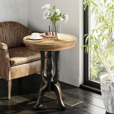 a chair and table in front of a window with flowers on the table next to it