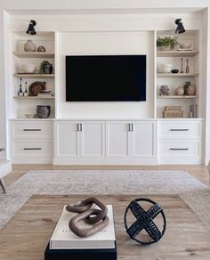 a living room with white built in cabinets and a flat screen tv