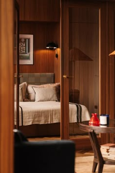 a bedroom with wood paneling and a bed in the corner next to a glass table