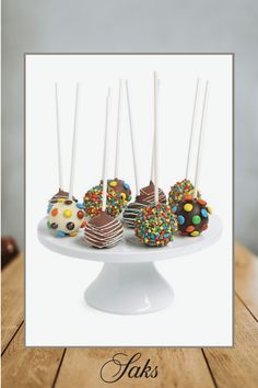 there are chocolate covered donuts with sprinkles on the cake plate and candy sticks sticking out of them