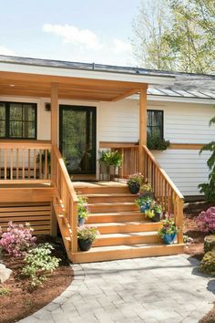 a small house with steps leading up to the front door and porch area, surrounded by landscaping