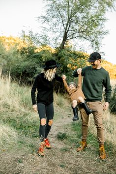 a man and woman walking down a dirt path with a child