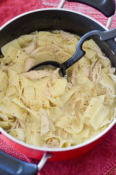 a pot filled with pasta and chicken on top of a red cloth