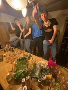 a group of people standing around a table with bottles on it