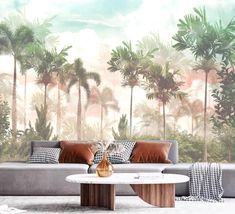 a living room with palm trees on the wall and couches in front of it