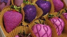 chocolate covered strawberries in pink and gold paper wrappers with purple frosting on them