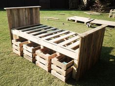 a bed frame made out of wooden pallets in the grass with benches around it