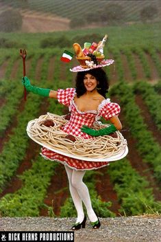 a woman in a red and white dress is holding a large plate with spaghetti on it