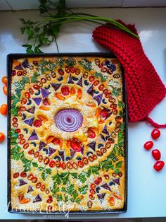 a colorful dish with vegetables on it next to a red knitted mitt and cherry tomatoes