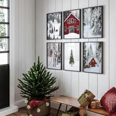 a small christmas tree in front of pictures on the wall next to a wooden bench