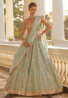 Elevate your style with our blue organza lehenga with mirror embroidery. This stunning ensemble features a luxurious organza lehenga adorned with intricate mirror and sequin embroidery in rose gold accents. Paired with a modern cut sleeveless blouse and a beautifully embellished dupatta featuring hand-cut mirrors, this set exudes elegance and sophistication. Perfect for a wedding reception, this lehenga set ensures the bride will make a memorable and dazzling impression on her special day. Composition : Lehenga - Organza, Dupatta - Organza, Blouse - Georgette Care: Dry Clean Only and Vacuum Storage This product can be customized for sleeves, length and colour Delivery : 6-8 weeks as the product is hand crafted. Check Size Guide or choose MySize for free customisation (All Sizes above XL ca Reception Dresses For Bridesmaids, Lehenga Sparkly, Lengha Modern, Modern Lehenga Designs, Blue Organza Lehenga, Mirror Blouse, Intricate Mirror, Pastel Lehenga, Mirror Sequin