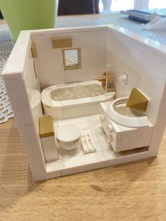 a dollhouse bathroom with a toilet, sink and bathtub in the middle of it