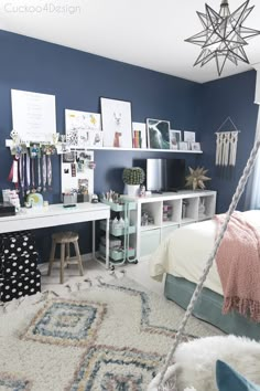 a bedroom with blue walls, white furniture and various pictures on the wall above it