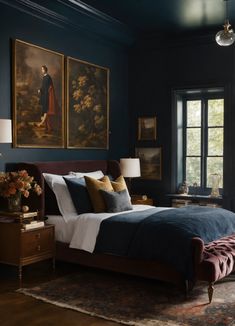 a bedroom with dark blue walls and paintings on the wall above the bed, along with a red velvet footstool