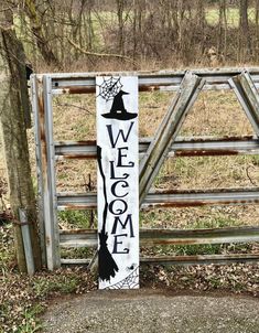 a welcome sign with a witch hat on it in front of a gate and fence