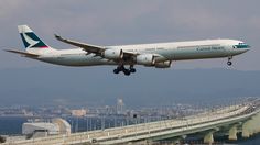 an airplane is flying low over the water near a bridge and city in the background