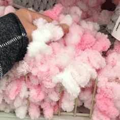 a person is reaching for some pink and white pom - poms