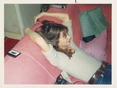 a woman laying on top of a pink couch