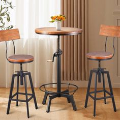 two stools and a table in a room with wooden floors, windows and curtains