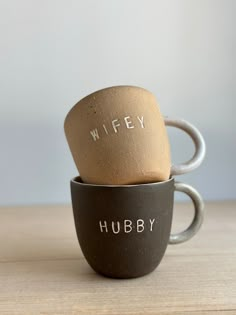 two coffee mugs with the words wife and hubby printed on them sitting side by side