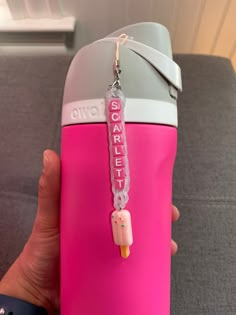 a person holding a pink water bottle with a keychain attached to it