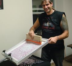 a man holding a piece of art while standing next to a table with an object on it