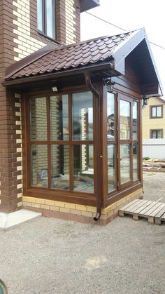 a small building with a wooden porch and glass doors on the side of it's windows