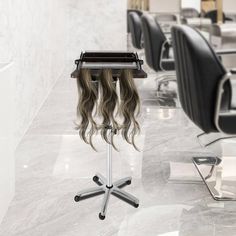 a hair salon with chairs and tables in the back ground, one chair has long wavy hair on it