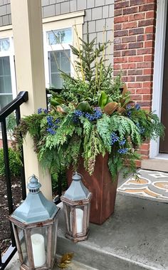 two blue lanterns are sitting on the front steps next to a planter filled with greenery