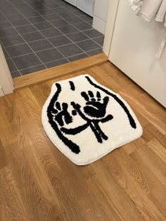 a white rug with black hand prints on it sitting on the floor in front of a door