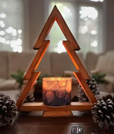 a lit candle sitting on top of a wooden table in front of a christmas tree