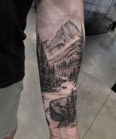 a man's arm with a mountain scene tattoo on the left side of his arm