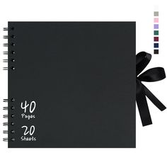 a black spiral bound notebook with white writing on the cover and ribbon tied around it