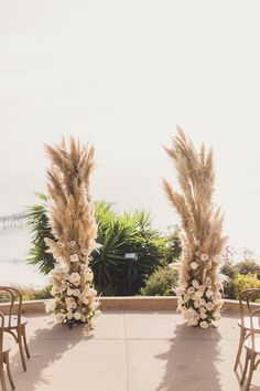 an outdoor ceremony set up with chairs and tall pamodia flowers on the aisle