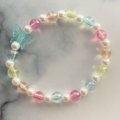 a bracelet with multicolored glass beads and a butterfly charm on top of it