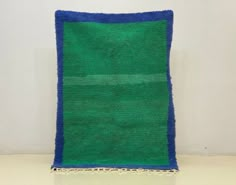 a green and blue rug sitting on top of a white floor