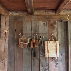 an old wooden wall with hanging utensils and bags on it's hooks