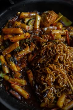 some noodles and vegetables are in a black bowl