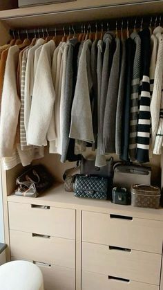 a closet filled with lots of sweaters and bags on top of wooden drawers next to a toilet