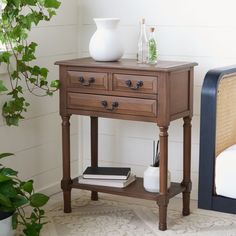 a small wooden table with two drawers and a vase on it next to a couch