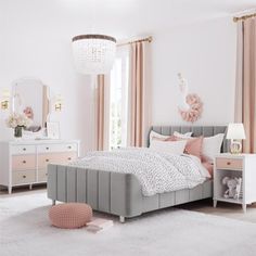 a bedroom decorated in pink and grey with white bedding, dressers, mirror and chandelier