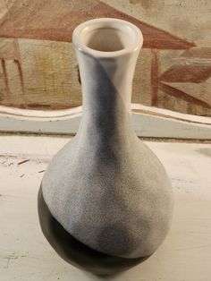 a white and gray vase sitting on top of a table