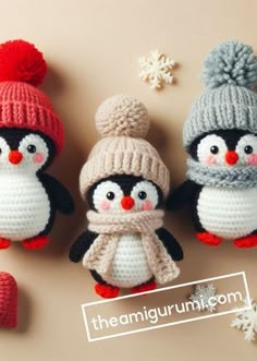 three crocheted penguins with hats and scarfs on top of a table next to snowflakes